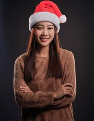 Portrait of beauty Asian woman wearing Santa-Claus hat with happy expression for Christmas celebration on dark background