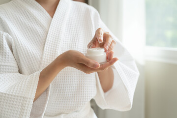 Close-up woman using skin care serum cream in daily routine.