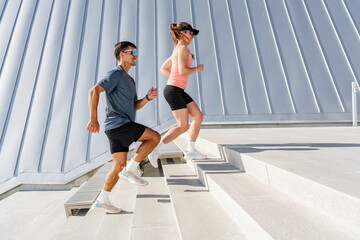 A man and woman running up stairs in sporty attire, showcasing endurance and athleticism outdoors.