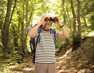 Mature male hiker looking through binoculars