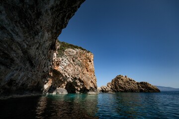 Fototapeta premium Coastal cliffs and the serene water of the Ionian sea under a blue sky in Zakynthos island, Greece