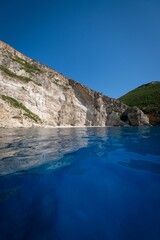 Obraz premium Vertical view of the blue waters and cliffs covered with lush green vegetation in Zakynthos, Greece