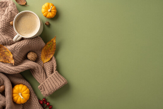 Warm autumn composition featuring a cup of coffee on a sweater surrounded by leaves and small pumpkins