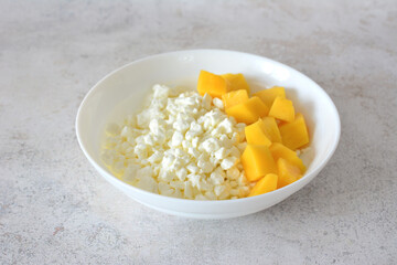 a bowl of diced mango and some cottage cheese isolated close up 