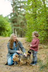 Mother and her little son walking their pedigreed Australian terrier dog in late autumn park. Fall portrait of black and sable tan purebred Australian terrier.