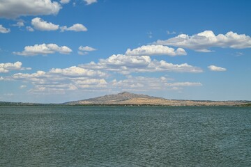 Scenic view of a tranquil lake under a cloudy blue sky on a sunny day in Spain
