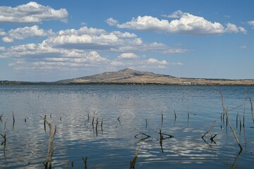 Scenic view of a tranquil lake under a cloudy blue sky on a sunny day in Spain