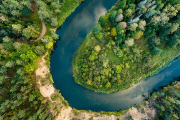 Aerial view of Sventoji river winding through autumn forest. Beautiful aerial forest scene near Anyksciai, Lithuania. Trees and river on sunny fall day.