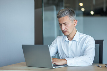 Focused Businessman Working on Laptop in Modern Office