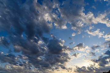 Beautiful white puffy clouds against blue sky during dramatic sunset