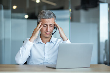 Stressed Businessman with Headset Using Laptop at Work