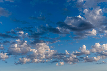 Beautiful white puffy clouds against blue sky during dramatic sunset