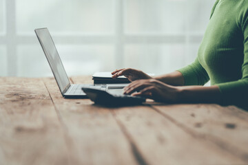 Naklejka premium Focused Work at Home Office: A close-up of a woman's hands diligently working on a laptop, showcasing the modern home office environment with natural light streaming through the window. The image evo