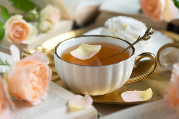On the white table there is hot tea, cakes and delicate roses.