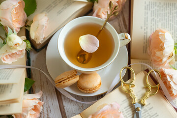 On the white table there is hot tea, cakes and delicate roses.