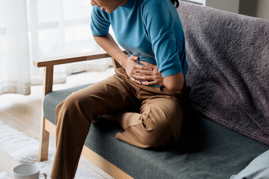 Woman has stomach ache and press hands to stomach due to menstrual cramps period cramps splenomegaly  food poisoning excess gas or acid