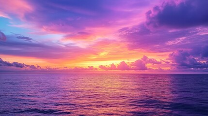 Obraz premium A dramatic sunset sky with vibrant oranges, pinks, and purples blending together over a calm ocean.