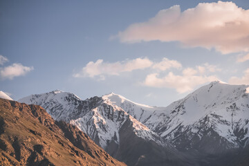 Landscape of the peaks of the mountains of the Wakhan Corridor with rocky mountain peaks with snow and glaciers in Tajikistan in the Pamirs, in the evening at sunset, minimalist landscape