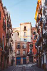 Venture into this charming alleyway adorned with vibrant buildings that warmly bask in the sunlight beams in Tarragona, Spain