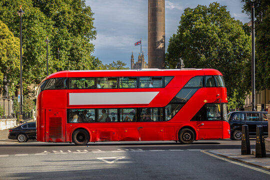 Ein roter Doppeldeckerbus mit freier Werbefl&auml;che oder Werbebanner f&auml;hrt durch eine von B&auml;umen ges&auml;umte Stra&szlig;e in London, Vereinigte K&ouml;nigreich Gro&szlig;britannien