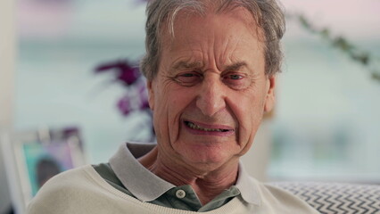 Elderly man pretending to be angry while sitting on the couch, showcasing a playful and humorous...