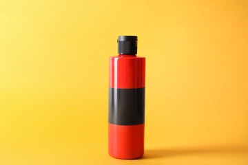 Red acrylic paint in bottle on orange background