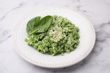Tasty spinach risotto served on white marble table, closeup