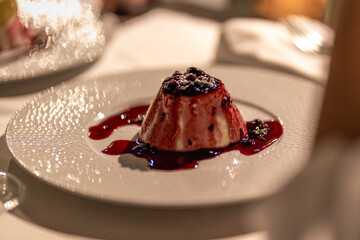 Savor a panna cotta dessert topped with assorted berries and delightful berry sauce, elegantly served