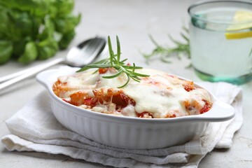 Delicious al forno pasta in baking dish on light table, closeup