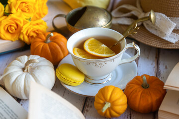 Cup of tea with orange and small pumpkins on white table, September.