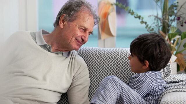 Grandfather and young boy engaging in a heartfelt conversation on the couch, emphasizing the close bond and meaningful connection between generations