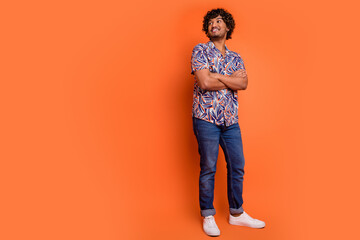 Full size photo of nice young man look empty space folded hands wear trendy colorful outfit isolated on orange color background