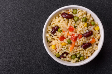 Boiled wheat bulgur porridge with vegetables peppers, peas, corn