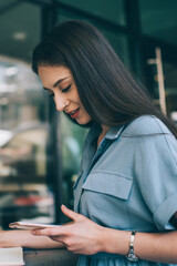 Glad freelancer browsing smartphone and writing in notepad