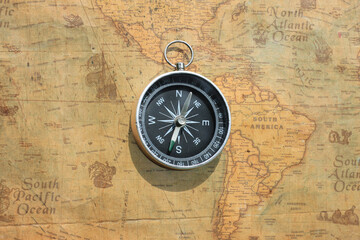 Classic round compass on background of old vintage map