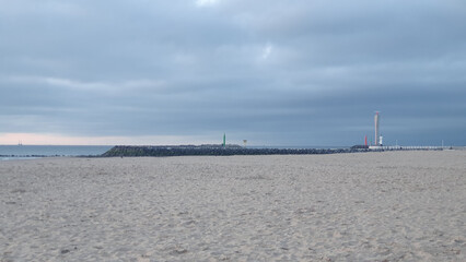 Beach at sunset. Much sand, water and clouds.