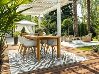 Fototapeta premium Beautiful modern garden with a wooden terrace, a table, and chairs on the deck. A gray patterned area rug is in front of it. A small gazebo with hanging plants and a wooden fence