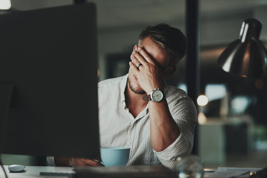 Night, man and tired at desk with headache, stress or anxiety for economy crash. Male accountant, budget issue or migraine in office with technology, depression or financial crisis or missed deadline