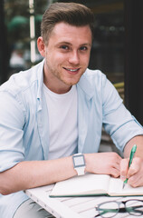 Cheerful guy making notes in outdoor terrace