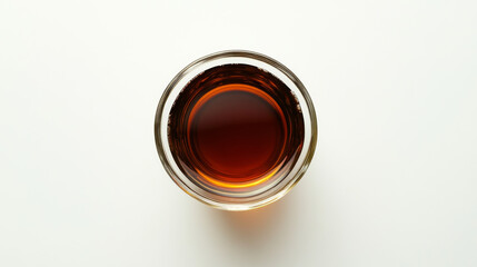 A black tea in a clear glass cup, seen from above, against a plain white backdrop.