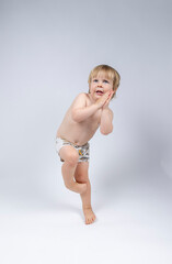Naklejka premium A young toddler plays on a white backdrop in a photo studio.