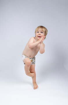 A young toddler plays on a white backdrop in a photo studio.