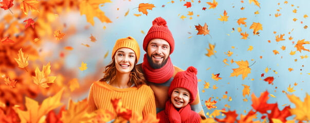 Fototapeta premium Portrait of happy man, woman and their child in warm sweaters, hats and scarfs standing under the falling autumnal leaves,