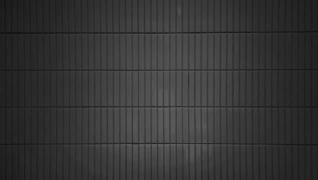 close up image of dark black ceramic clay wall tiles use as background with blank space for design. interior wall finishing material. metro tiles background. subway brick in vertical pattern.