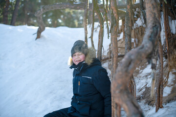 The boy walks through the snow-covered forest and enjoys the beauty of the winter landscape.