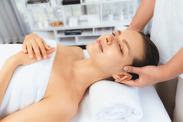 Caucasian woman enjoying relaxing anti-stress head massage and pampering facial beauty skin recreation leisure in dayspa modern light ambient at luxury resort or hotel spa salon. Quiescent