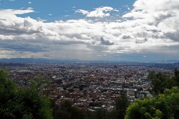 Panoramic view of a sprawling cityscape of Bogota with a mix of buildings under a partly cloudy sky