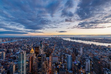 Fototapeta premium Aerial view of New York City skyline at sunset with dramatic clouds and the Hudson River