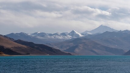 Snow-capped mountains and blue lake under a cloudy sky