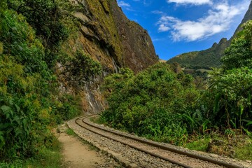 Fototapeta premium Scenic railway track winding through lush green mountains leading to Aguas Calientes